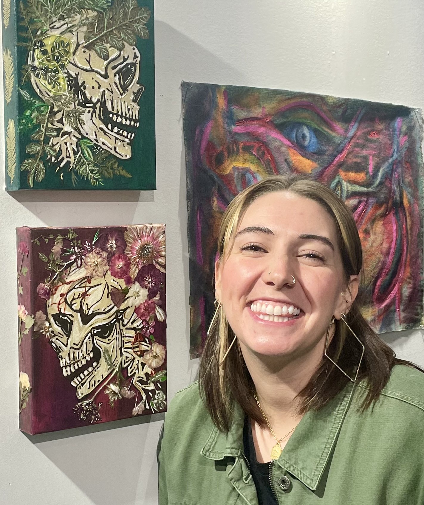 woman wearing a green jacket in front of three paintings